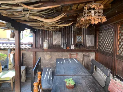 a wooden table with benches and a chandelier at Карагьозовата Къща - цяла къща - 6 големи спални, 6 бани и отделна механа in Koprivshtitsa