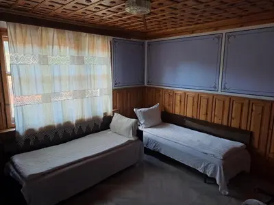 a room with two beds and a window at Карагьозовата Къща - цяла къща - 6 големи спални, 6 бани и отделна механа in Koprivshtitsa