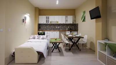 a bedroom with a bed and a table and a kitchen at Студио Young Gogh in Pamporovo