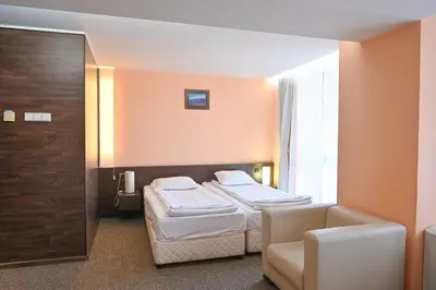 a hotel room with two beds and a chair at Хотел Елица in Bansko