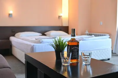 a bottle of whiskey and two glasses on a table in a hotel room at Хотел Елица in Bansko