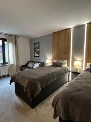 a bedroom with two beds and a couch at Devonshire Lodge Chalet in Bansko