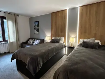 a bedroom with two beds and a couch at Devonshire Lodge Chalet in Bansko