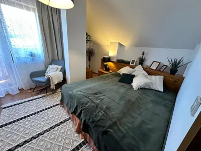 a bedroom with a bed and a chair and a window at Murphys Lodge panorama apartment in Bansko