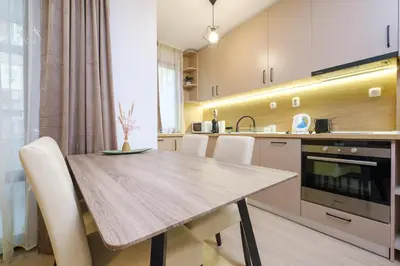 a kitchen with a wooden table and white chairs at Comfort 1 Bedroom App in Plovdiv