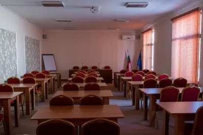 an empty classroom with desks and chairs and windows at Hotel Paradise in Ognyanovo