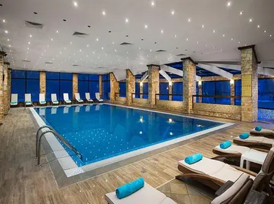 a large swimming pool in a building with chairs at СПА апартамент 