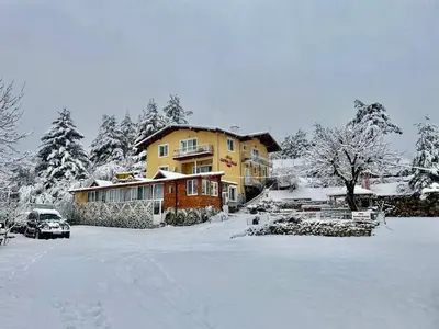 a house is covered in snow in a yard at Къща за гости 