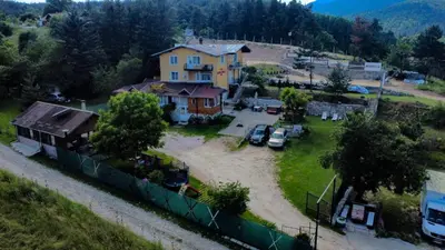 a house on a hill with cars parked in a yard at Къща за гости 