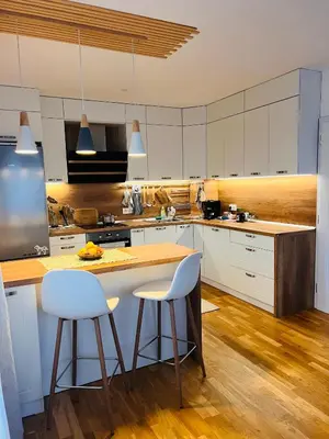 a kitchen with white cabinets and a island with bar stools at Cosy Dream Appartment near Borovets in Samokov