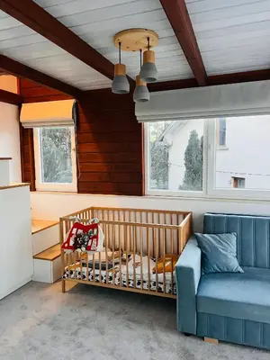 a baby crib in a room with a couch and windows at Cosy Dream Appartment near Borovets in Samokov