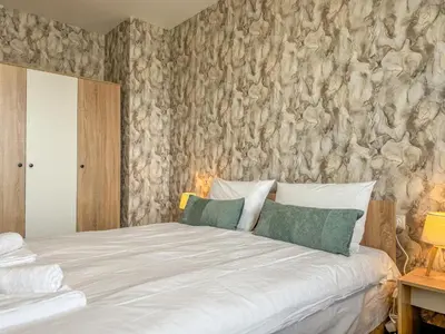 a bedroom with a white bed with a wall at One-Bedroom Apartment next to Mall Plovdiv with Free Street Parking in Plovdiv
