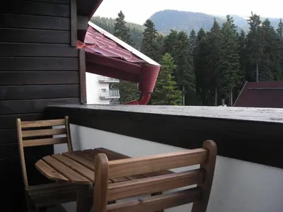a wooden chair sitting on the balcony of a house at Iglika 2 Top Floor apartment in Borovets