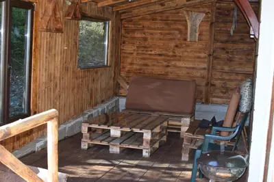a porch of a log cabin with a bench and a chair at Villa Pamporovo in Pamporovo