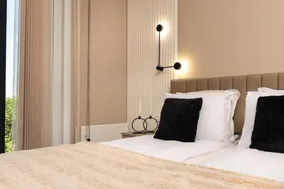 a bedroom with a bed with white sheets and black pillows at Royal Garden apartment with Private Parking in Plovdiv