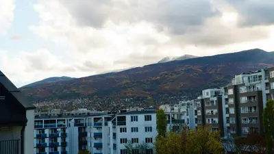 a city with buildings and mountains in the background at The BlackPeak View Apartment in Sofia