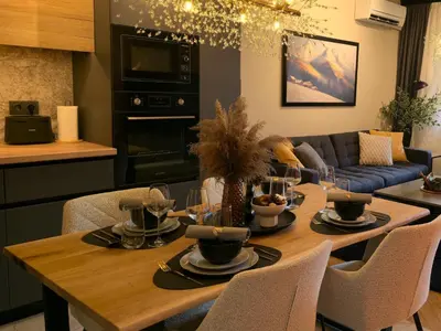 a kitchen and living room with a wooden table with chairs at LUXURY Designer Apt I Meters to Gondola Lift I Sleeps 6 I Pool & Parking I in Bansko