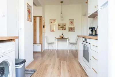 a kitchen with white cabinets and a table at Old Town Bijou in Sofia