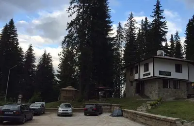 a building with cars parked in a parking lot at Семеен хотел Гингеръ in Pamporovo