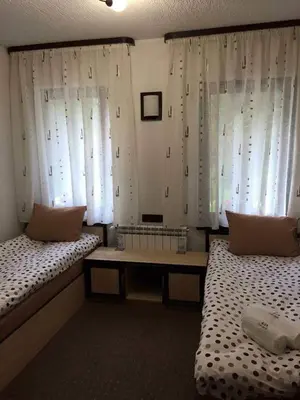 a room with two beds and a table and windows at Семеен хотел Гингеръ in Pamporovo