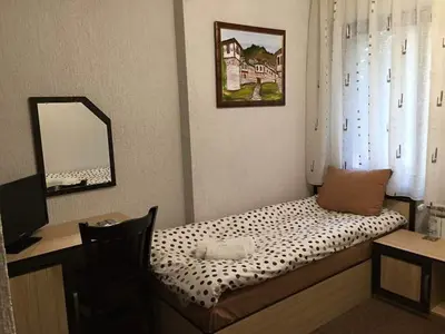 a room with a bed with a desk and a mirror at Семеен хотел Гингеръ in Pamporovo