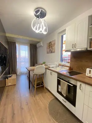 a kitchen with white cabinets and a table and a sink at Beautiful 2BD Apartment with Large Terrace and Free Parking in Plovdiv