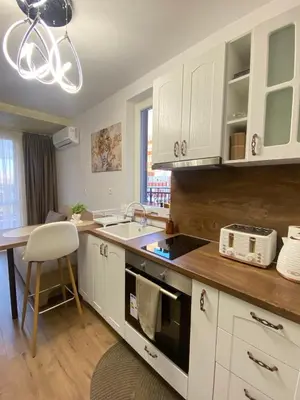 a kitchen with white cabinets and a sink and a table at Beautiful 2BD Apartment with Large Terrace and Free Parking in Plovdiv
