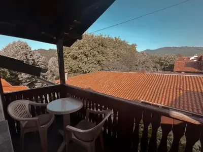 a balcony with a table and chairs and a roof at Къща за гости Орешака in Oreshak