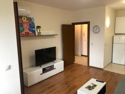 a living room with a flat screen tv on a white cabinet at Artistic Neon Apartment in Bansko