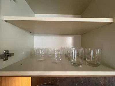 a row of empty glasses sitting on a shelf at New Urban Stay Airport city center metro access in Sofia