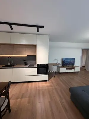 a kitchen with white cabinets and a living room at New Urban Stay Airport city center metro access in Sofia