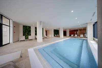 a large swimming pool in a building with chairs and tables at Hotel Complex SamElyon in Samokov