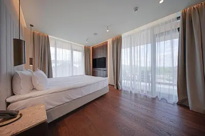 a bedroom with a large bed and large windows at Hotel Complex SamElyon in Samokov
