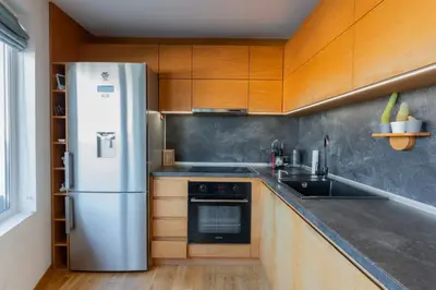 a kitchen with a stainless steel refrigerator and wooden cabinets at Luna Penthouse Stunning Sofia Skyline plus FREE Parking in Sofia
