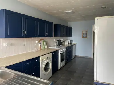 a kitchen with blue cabinets and a washer and dryer at Райска тишина in Zlatitsa