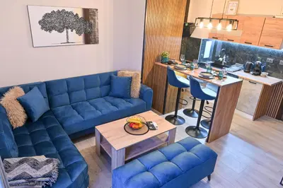 a living room with a blue couch and a table at Two Modern Apartments in One Building by SI Stay in Bansko