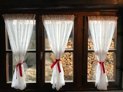 a window with white curtains and red bows at Chalet Jora - Total Chalets in Bansko