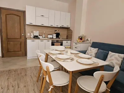 a dining room table with chairs and a kitchen at Apartment Bee Happy, Pchelinski Bani,Hot mineral water in Pchelin