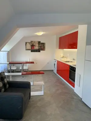 a living room with a couch and a kitchen with red cabinets at Stylish 1BR near Centre in Sofia