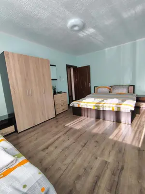 a bedroom with two beds and a wooden floor at Вила Владислава - стаи за гости in Cherni Vit