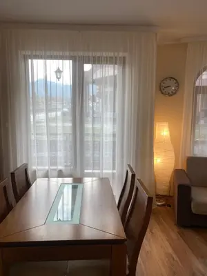 a dining table and chairs in a living room with a window at Cedar Lodge Apartament - Gondola in Bansko