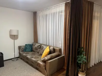 a living room with a couch in front of a window at Comfortable and affordable big studio in Bansko