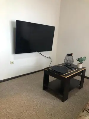 a living room with a table and a flat screen tv at Comfortable and affordable big studio in Bansko