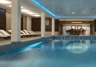 a pool in a hotel with chairs and a piano at Green Life Private Apartment D27 in Bansko