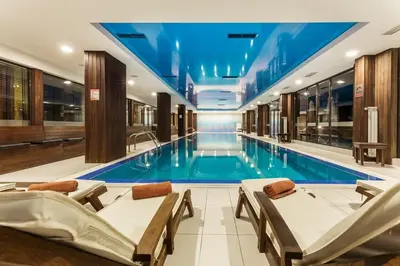 a swimming pool in a hotel with chairs and a swimming pool at Warm Evenings and free Bottle of Wine in Perun Lodge in Bansko
