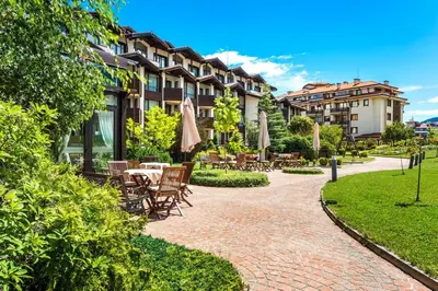 a patio with tables and chairs and umbrellas at Warm Evenings and free Bottle of Wine in Perun Lodge in Bansko