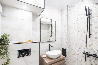 a white bathroom with a sink and a mirror at Panoramic View Cozy 1BR Apartment in Plovdiv