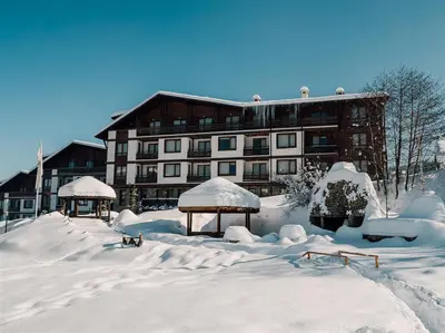 a snow covered building in front of a building at Superior studio with terrace in 4star Green Life Bansko in Bansko