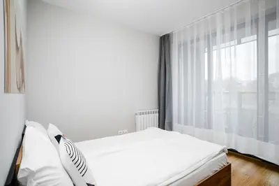 a white bedroom with a bed and a window at Modern Stay with Balcony in Sofia