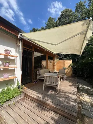 a patio with awning and a table and chairs at Cozy frame house in the wood
